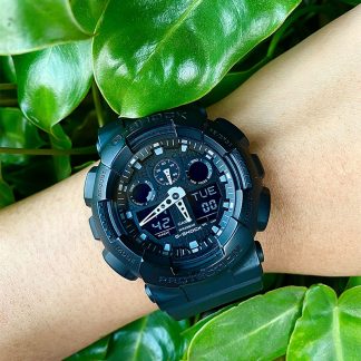 A black digital watch on a person's wrist over green background.