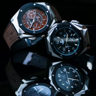 Brown and black traditional watches over mirrored glass.